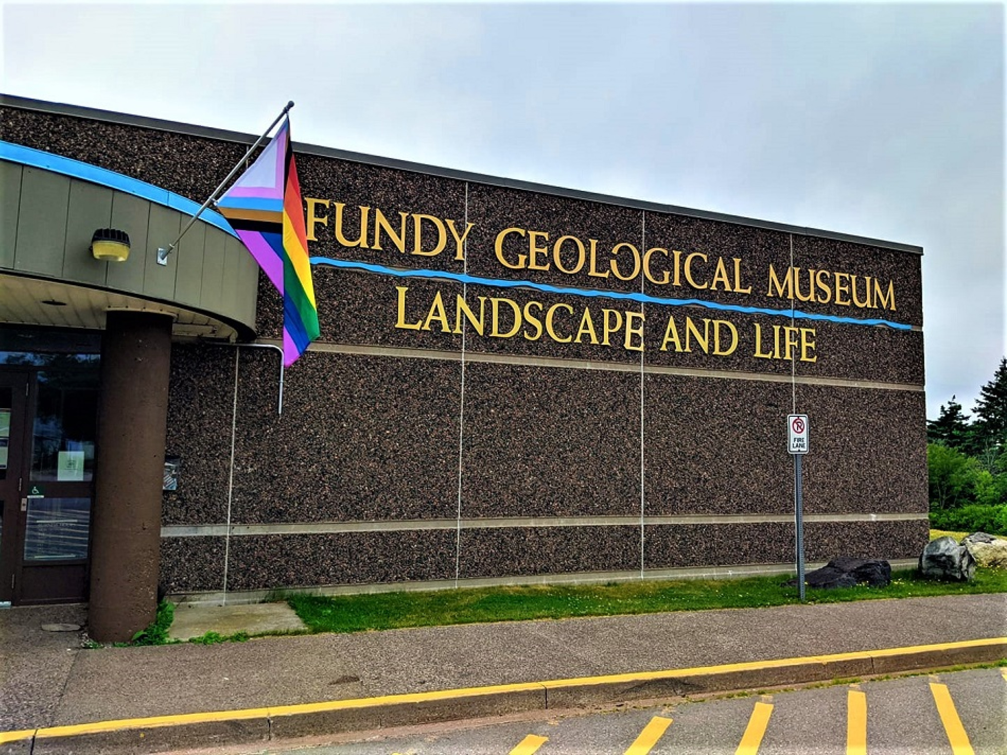 Exterior of the Fundy Geological Museum with the Pride Flag flying.