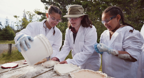 Two girls learning from a female Paleontologist.
